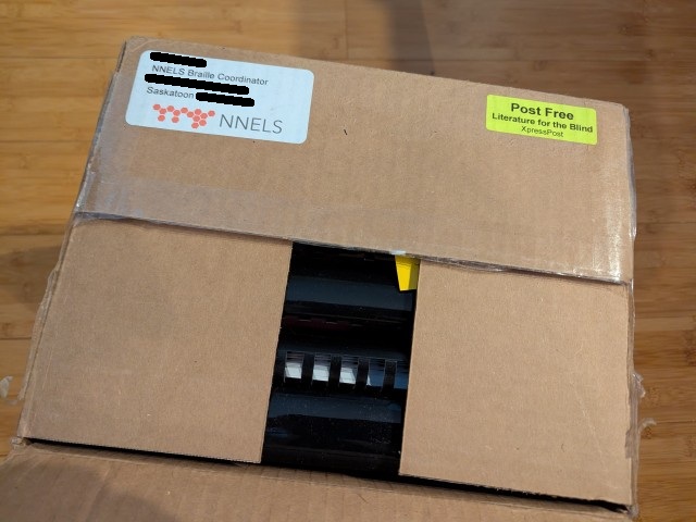 A carboard parcel from NNELS, but this time it's partially opened, revealing binders inside.
